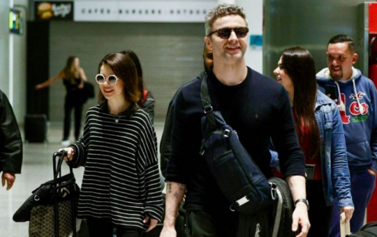 Sandy e Lucas Lima desembarcam sorridentes em aeroporto